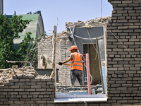 A builder is working to rebuild one of the sections of the five-storey apartment building at 44 Sobornyi Avenue that was destroyed by the Ru...