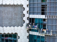 Workers are installing a glass curtain wall outside a high-rise building in Huai'an, China, on July 25, 2024. (