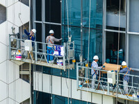 Workers are installing a glass curtain wall outside a high-rise building in Huai'an, China, on July 25, 2024. (