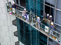 Workers are installing a glass curtain wall outside a high-rise building in Huai'an, China, on July 25, 2024. (