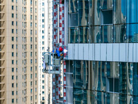 Workers are installing a glass curtain wall outside a high-rise building in Huai'an, China, on July 25, 2024. (