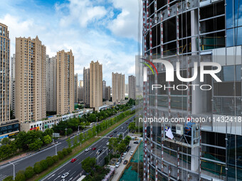 Workers are installing a glass curtain wall outside a high-rise building in Huai'an, China, on July 25, 2024. (