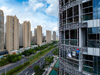 Workers are installing a glass curtain wall outside a high-rise building in Huai'an, China, on July 25, 2024. (