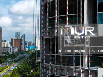 Workers are installing a glass curtain wall outside a high-rise building in Huai'an, China, on July 25, 2024. (