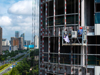 Workers are installing a glass curtain wall outside a high-rise building in Huai'an, China, on July 25, 2024. (