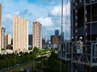 Workers are installing a glass curtain wall outside a high-rise building in Huai'an, China, on July 25, 2024. (