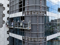 Workers are installing a glass curtain wall outside a high-rise building in Huai'an, China, on July 25, 2024. (