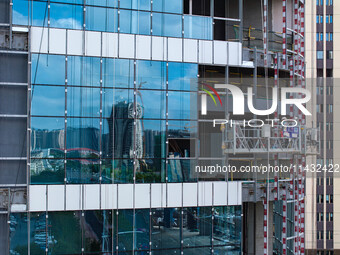 Workers are installing a glass curtain wall outside a high-rise building in Huai'an, China, on July 25, 2024. (