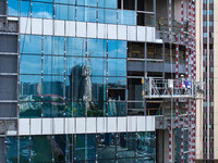 Workers are installing a glass curtain wall outside a high-rise building in Huai'an, China, on July 25, 2024. (