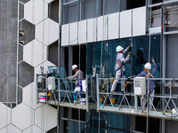 Workers are installing a glass curtain wall outside a high-rise building in Huai'an, China, on July 25, 2024. (