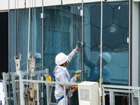 Workers are installing a glass curtain wall outside a high-rise building in Huai'an, China, on July 25, 2024. (