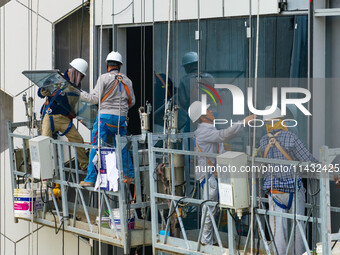 Workers are installing a glass curtain wall outside a high-rise building in Huai'an, China, on July 25, 2024. (