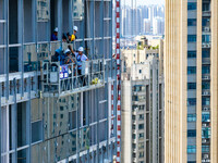 Workers are installing a glass curtain wall outside a high-rise building in Huai'an, China, on July 25, 2024. (