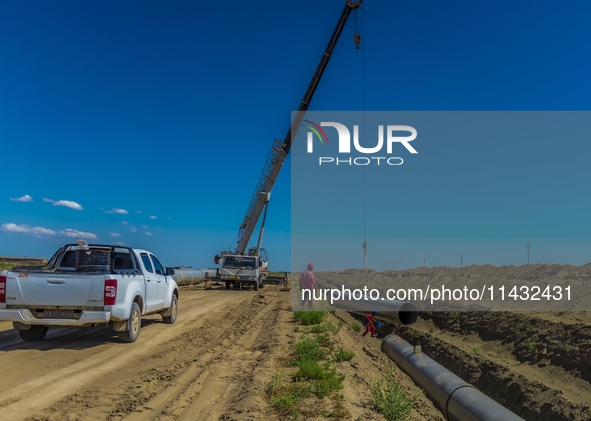 Workers are installing fiberglass tubes in a high-standard farmland in Karamay, China, on July 24, 2024. 