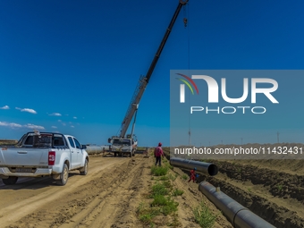 Workers are installing fiberglass tubes in a high-standard farmland in Karamay, China, on July 24, 2024. (