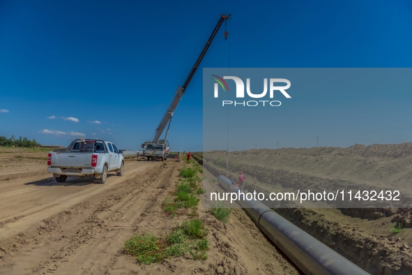 Workers are installing fiberglass tubes in a high-standard farmland in Karamay, China, on July 24, 2024. 