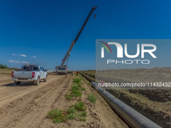 Workers are installing fiberglass tubes in a high-standard farmland in Karamay, China, on July 24, 2024. (