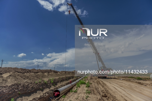 Workers are installing fiberglass tubes in a high-standard farmland in Karamay, China, on July 24, 2024. 