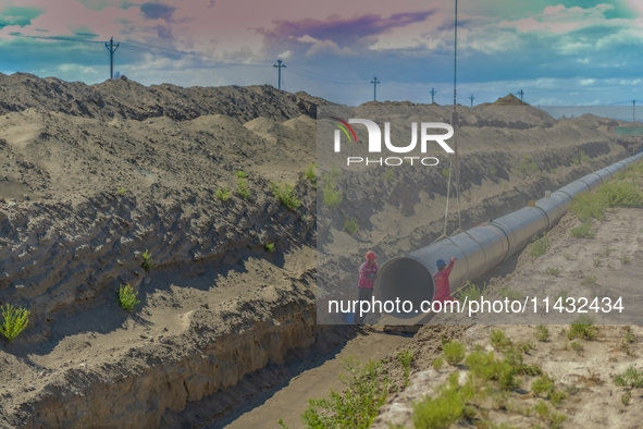 Workers are installing fiberglass tubes in a high-standard farmland in Karamay, China, on July 24, 2024. 