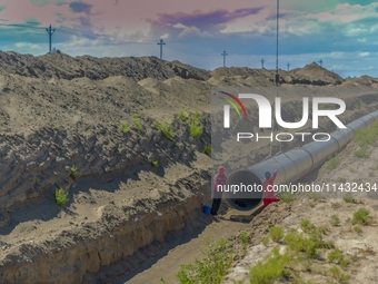 Workers are installing fiberglass tubes in a high-standard farmland in Karamay, China, on July 24, 2024. (