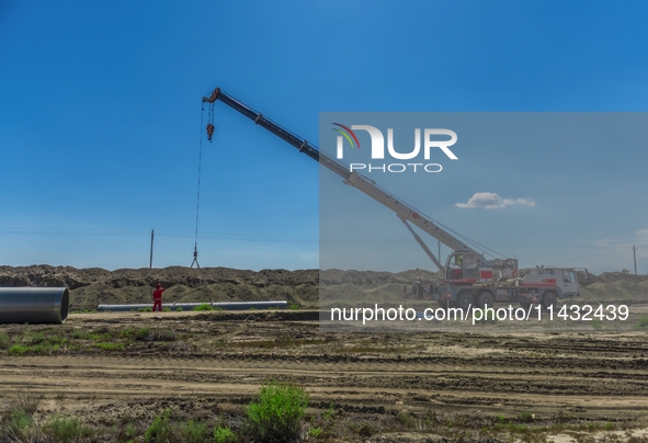 Workers are installing fiberglass tubes in a high-standard farmland in Karamay, China, on July 24, 2024. 