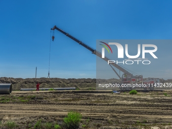 Workers are installing fiberglass tubes in a high-standard farmland in Karamay, China, on July 24, 2024. (