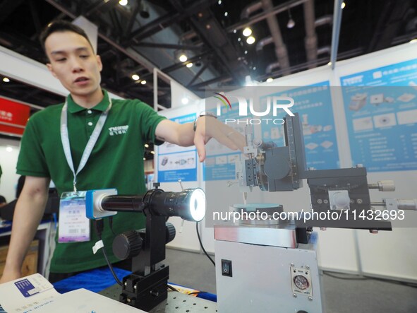 A staff member is demonstrating a ''bare fiber grinder'' at the ''Fifth World Photonic Congress 2024'' in Beijing, China, on July 25, 2024. 