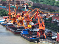 Cranes are unloading coal from a cargo ship on the Yangtze River at the raw material terminal of Meishan Iron and Steel Plant in Nanjing, Ch...