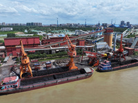 Cranes are unloading coal from a cargo ship on the Yangtze River at the raw material terminal of Meishan Iron and Steel Plant in Nanjing, Ch...