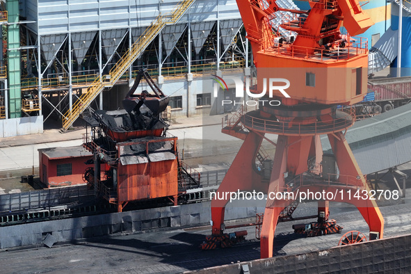 Cranes are unloading coal from a cargo ship on the Yangtze River at the raw material terminal of Meishan Iron and Steel Plant in Nanjing, Ch...