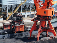 Cranes are unloading coal from a cargo ship on the Yangtze River at the raw material terminal of Meishan Iron and Steel Plant in Nanjing, Ch...