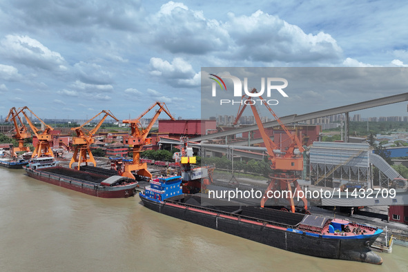 Cranes are unloading coal from a cargo ship on the Yangtze River at the raw material terminal of Meishan Iron and Steel Plant in Nanjing, Ch...