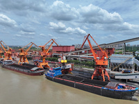 Cranes are unloading coal from a cargo ship on the Yangtze River at the raw material terminal of Meishan Iron and Steel Plant in Nanjing, Ch...