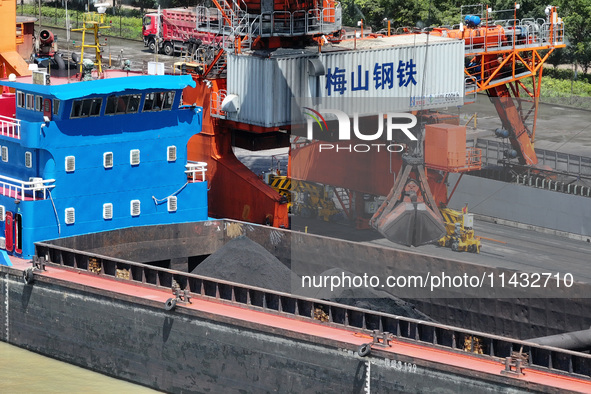 Cranes are unloading coal from a cargo ship on the Yangtze River at the raw material terminal of Meishan Iron and Steel Plant in Nanjing, Ch...