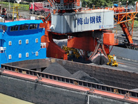 Cranes are unloading coal from a cargo ship on the Yangtze River at the raw material terminal of Meishan Iron and Steel Plant in Nanjing, Ch...