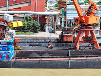 Cranes are unloading coal from a cargo ship on the Yangtze River at the raw material terminal of Meishan Iron and Steel Plant in Nanjing, Ch...