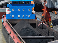 Cranes are unloading coal from a cargo ship on the Yangtze River at the raw material terminal of Meishan Iron and Steel Plant in Nanjing, Ch...