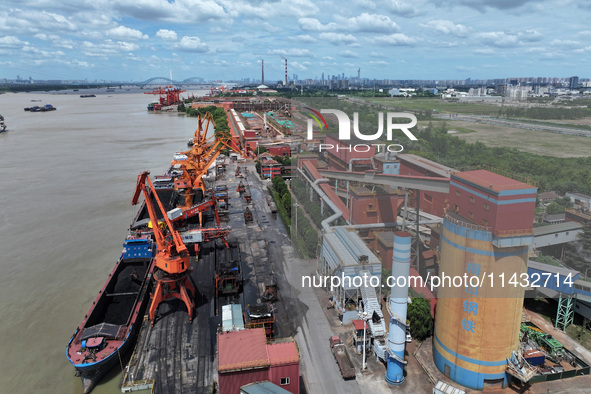 Cranes are unloading coal from a cargo ship on the Yangtze River at the raw material terminal of Meishan Iron and Steel Plant in Nanjing, Ch...