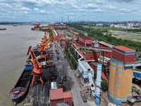 Cranes are unloading coal from a cargo ship on the Yangtze River at the raw material terminal of Meishan Iron and Steel Plant in Nanjing, Ch...