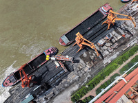 Cranes are unloading coal from a cargo ship on the Yangtze River at the raw material terminal of Meishan Iron and Steel Plant in Nanjing, Ch...