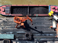 Cranes are unloading coal from a cargo ship on the Yangtze River at the raw material terminal of Meishan Iron and Steel Plant in Nanjing, Ch...