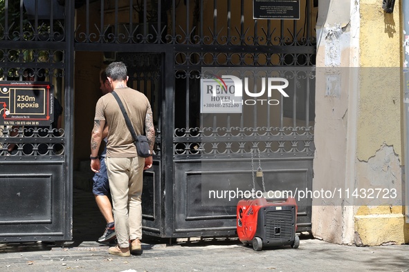 Men are stepping through the gate near a diesel generator used as a backup during power outages in Odesa, Ukraine, on July 23, 2024. NO USE...