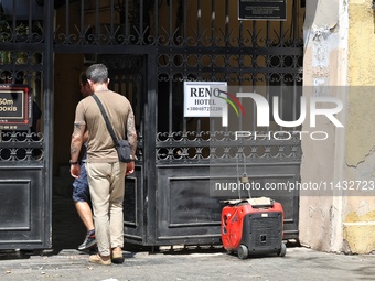 Men are stepping through the gate near a diesel generator used as a backup during power outages in Odesa, Ukraine, on July 23, 2024. NO USE...