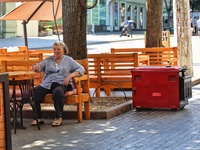 A woman is sitting at an outdoor cafe near a diesel generator used as a backup during power outages in Odesa, Ukraine, on July 23, 2024. NO...