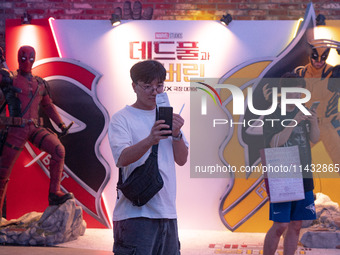 A man is taking a selfie with his movie ticket in front of a billboard of Marvel Studios movie 'Deadpool & Wolverine' in Seoul, South Korea,...