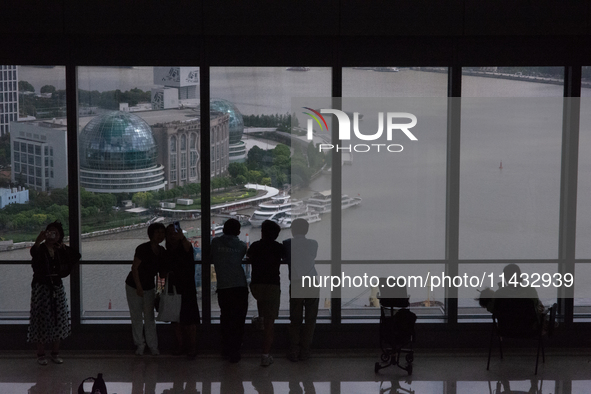 Several people are taking a look at the Huangpu River in a cafe as dark clouds are seen above the Huangpu River in Shanghai, China, on July...