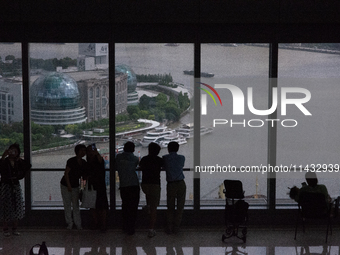 Several people are taking a look at the Huangpu River in a cafe as dark clouds are seen above the Huangpu River in Shanghai, China, on July...