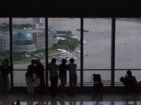 Several people are taking a look at the Huangpu River in a cafe as dark clouds are seen above the Huangpu River in Shanghai, China, on July...