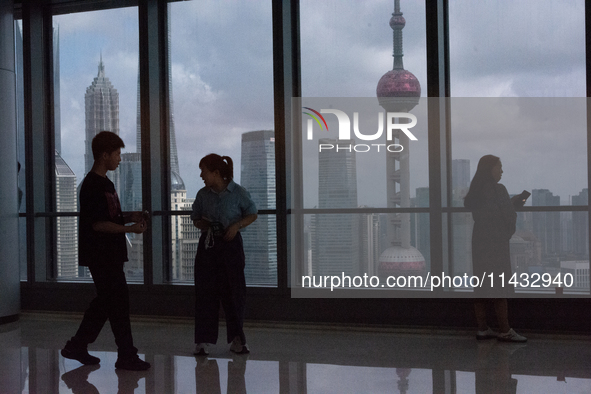 Several people are taking a look at the Huangpu River in a cafe as dark clouds are seen above the Huangpu River in Shanghai, China, on July...