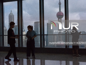 Several people are taking a look at the Huangpu River in a cafe as dark clouds are seen above the Huangpu River in Shanghai, China, on July...